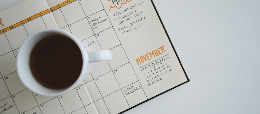 Agenda mensuel et tasse de café sur un bureau