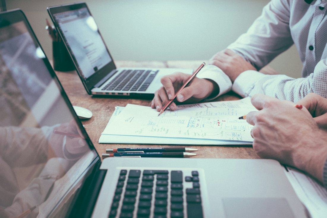 Deux personnes examinent des documents devant un ordinateur portable